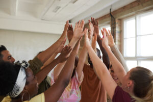 Team of people during training Group of young people raising their hands and supporting each other during training